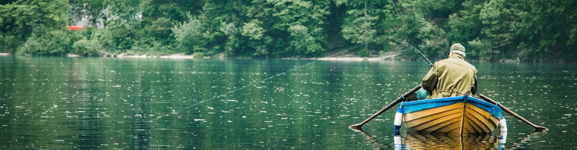 senior man on a boat fishing a small lake